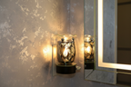Silver leaf wall plug-in oil burner beside bathroom mirror glowing bright warm golden light