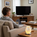 Woman relaxing on couch with White Drizzles lamp glowing beside her