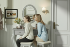 Mom and daughter looking in mirror together at grey vanity